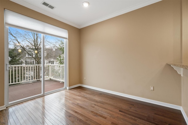 unfurnished room featuring baseboards, visible vents, hardwood / wood-style floors, and ornamental molding