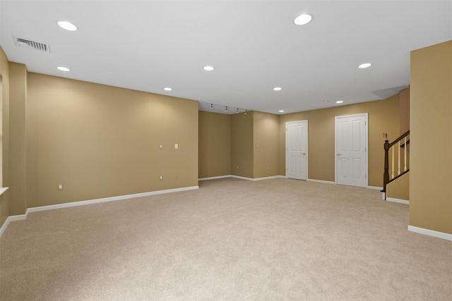 below grade area featuring light colored carpet, recessed lighting, visible vents, baseboards, and stairway