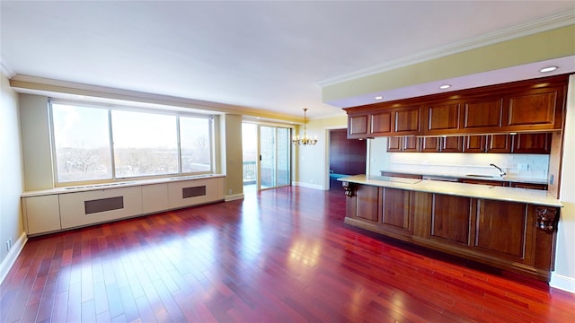 kitchen featuring crown molding, dark wood-type flooring, hanging light fixtures, and a chandelier