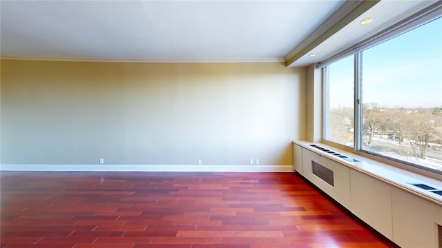 empty room with a wealth of natural light, dark hardwood / wood-style flooring, and ornamental molding