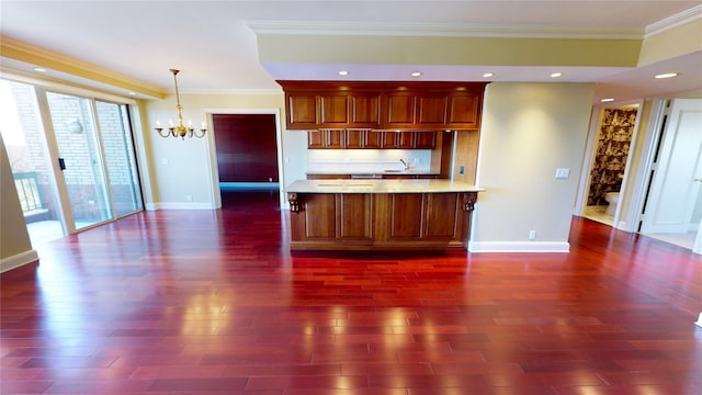 kitchen featuring pendant lighting, dark wood-type flooring, an inviting chandelier, ornamental molding, and kitchen peninsula