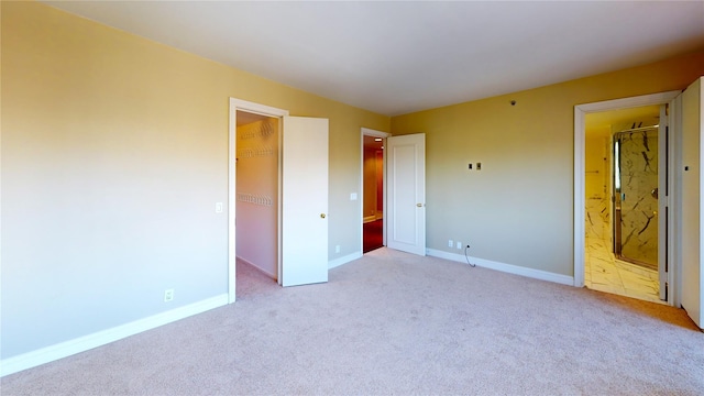 unfurnished bedroom with a spacious closet, light carpet, and a closet