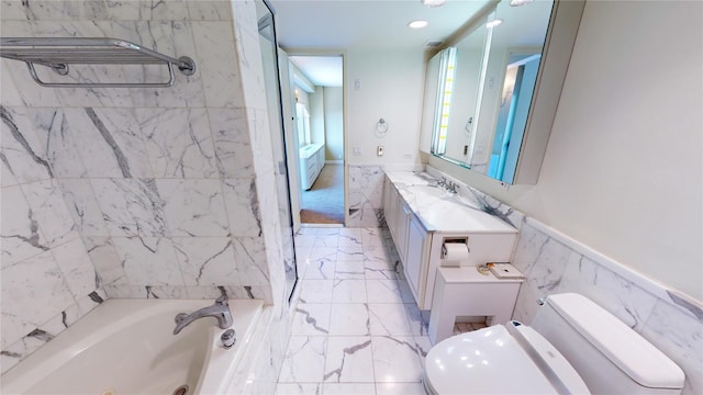 bathroom with a bathtub, vanity, tile walls, and toilet