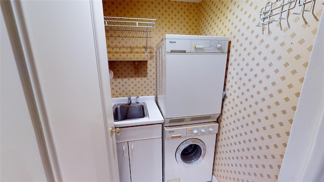 laundry room featuring cabinets, stacked washer / dryer, and sink