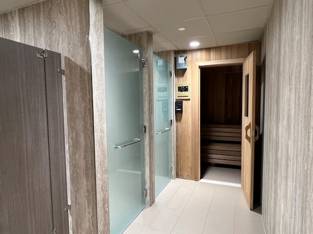 bathroom with tile patterned floors, a paneled ceiling, wood walls, and an enclosed shower