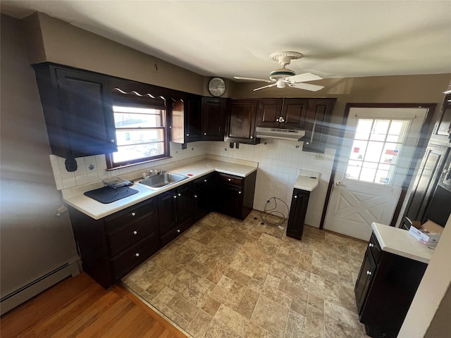 kitchen with decorative backsplash, dark brown cabinets, ceiling fan, sink, and a baseboard radiator