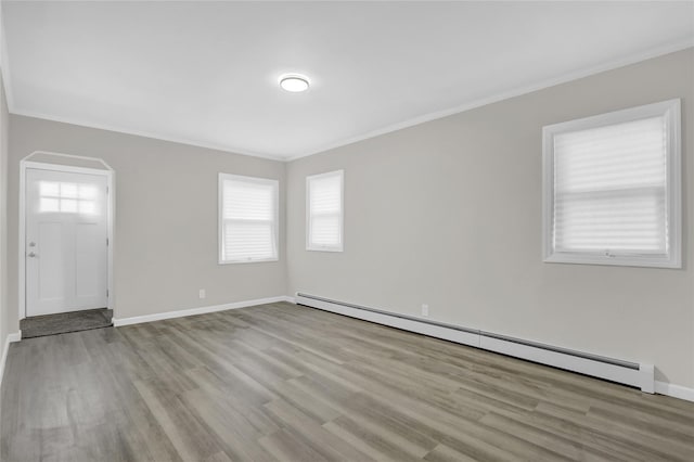 unfurnished room featuring ornamental molding, light hardwood / wood-style floors, and a baseboard heating unit