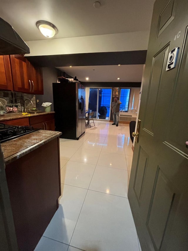 kitchen with backsplash, black appliances, ventilation hood, sink, and light tile patterned flooring