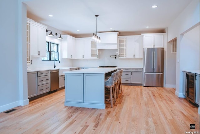 kitchen featuring white cabinets, gray cabinets, a kitchen bar, and stainless steel appliances