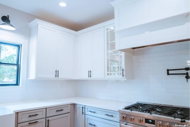 kitchen with stainless steel range, tasteful backsplash, and white cabinetry