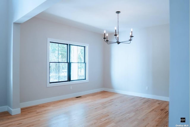 unfurnished room with light hardwood / wood-style flooring and a notable chandelier