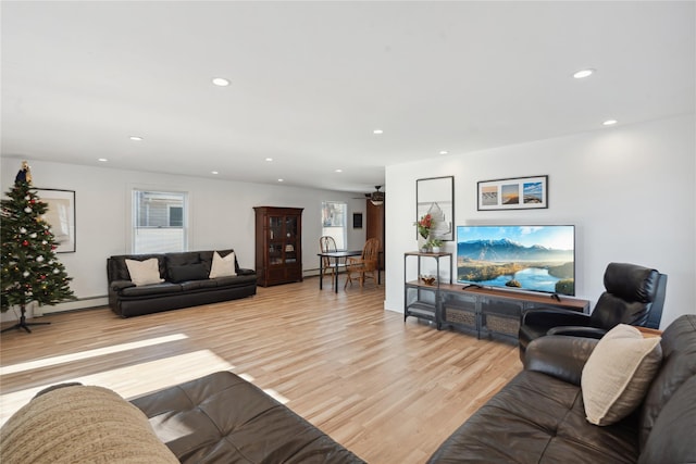 living room with ceiling fan, light hardwood / wood-style floors, and a baseboard heating unit