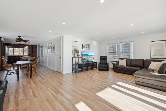 living room with ceiling fan, light hardwood / wood-style flooring, and sink