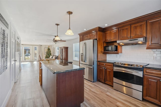 kitchen with dark stone countertops, light hardwood / wood-style flooring, a kitchen island, and appliances with stainless steel finishes