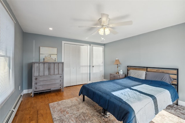 bedroom featuring hardwood / wood-style flooring, ceiling fan, and a baseboard heating unit