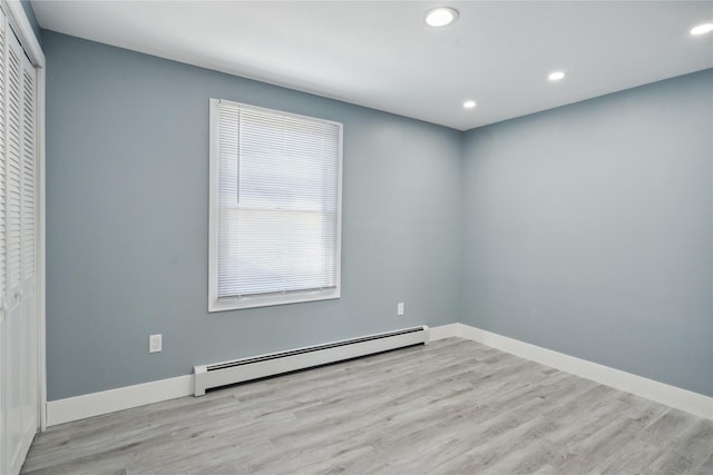 empty room featuring a baseboard radiator and light hardwood / wood-style flooring