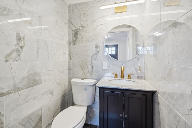 bathroom with vanity, toilet, and tile walls