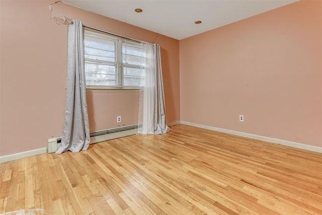 empty room with baseboard heating and light wood-type flooring