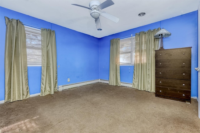 empty room with carpet floors, a baseboard radiator, a wealth of natural light, and ceiling fan