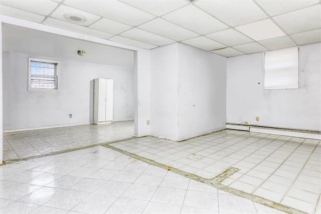 tiled spare room with baseboard heating and a drop ceiling