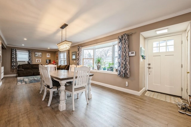 dining space with a notable chandelier, plenty of natural light, wood-type flooring, and ornamental molding