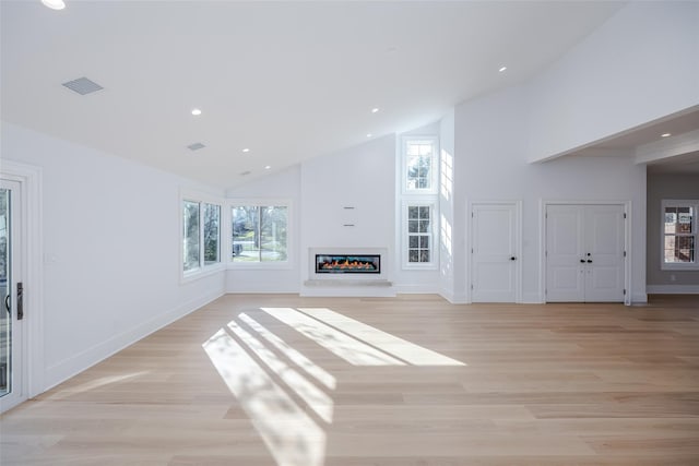 unfurnished living room with light wood-type flooring and high vaulted ceiling