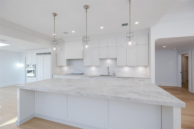 kitchen with backsplash, white cabinets, a spacious island, light wood-type flooring, and cooktop