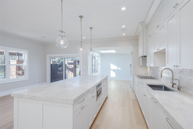 kitchen with white cabinetry, a large island, sink, and pendant lighting