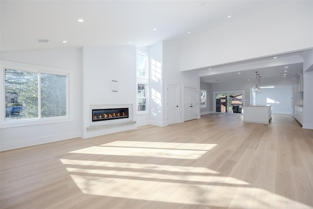 unfurnished living room with high vaulted ceiling, light hardwood / wood-style flooring, and plenty of natural light