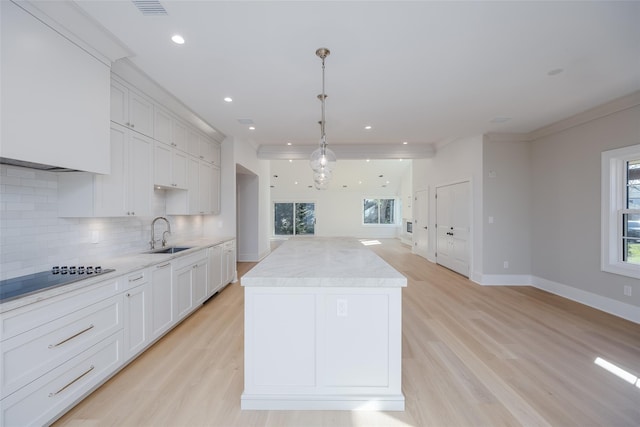 kitchen with white cabinets, light wood-type flooring, black electric cooktop, and hanging light fixtures