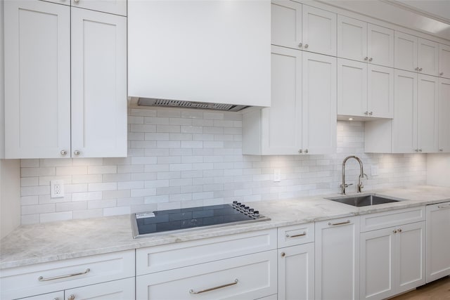 kitchen with backsplash, black stovetop, white cabinetry, and sink