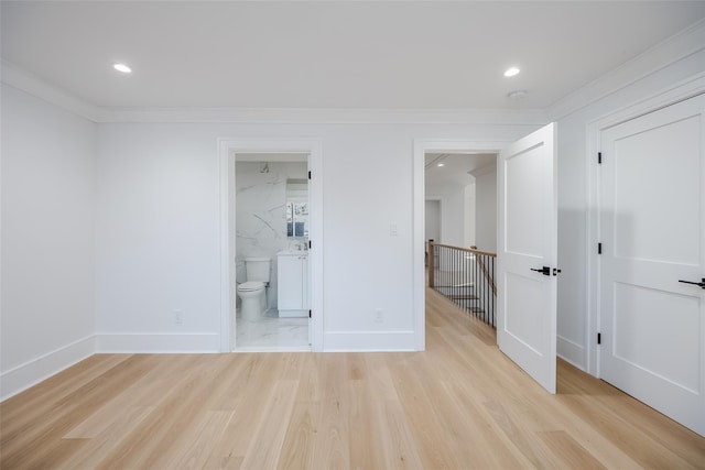 unfurnished bedroom with light hardwood / wood-style floors, crown molding, and connected bathroom