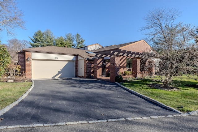 view of front of home featuring a front yard, driveway, an attached garage, a pergola, and brick siding