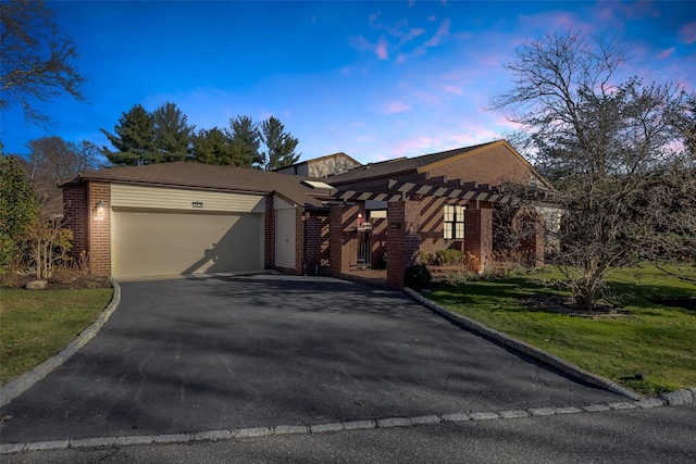 view of front facade featuring aphalt driveway, a garage, a front yard, and brick siding