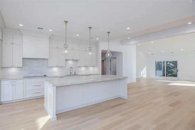 kitchen featuring decorative backsplash, a large island, white cabinetry, and a sink