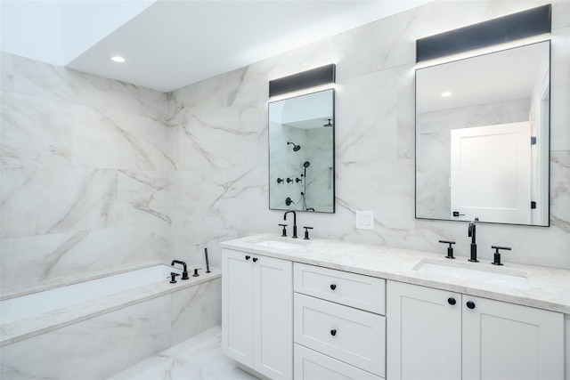 bathroom featuring a sink, a marble finish shower, a garden tub, and tile walls