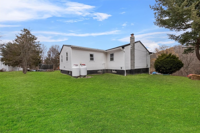 rear view of house with a lawn and a trampoline