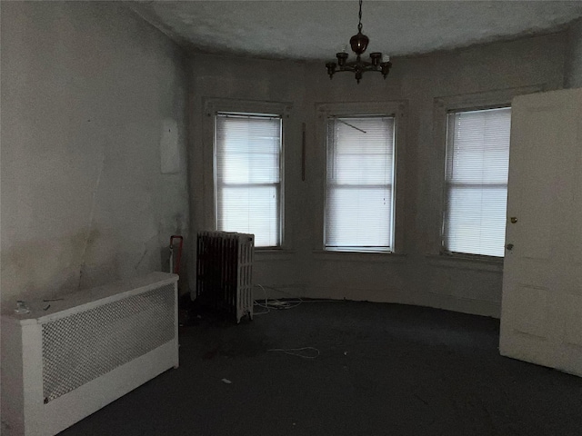 unfurnished dining area with radiator and a chandelier