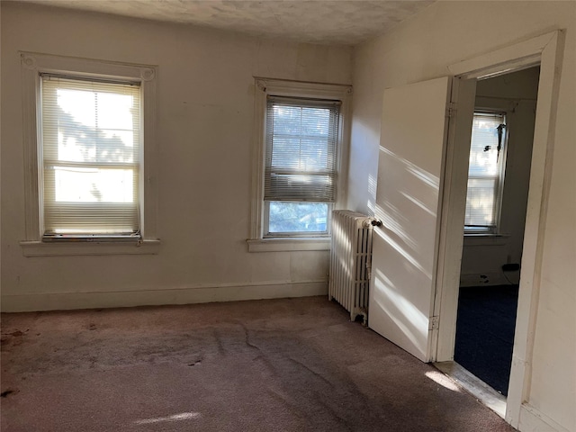 carpeted empty room featuring radiator