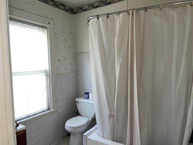 full bathroom with shower / tub combo with curtain, a healthy amount of sunlight, tile walls, and toilet