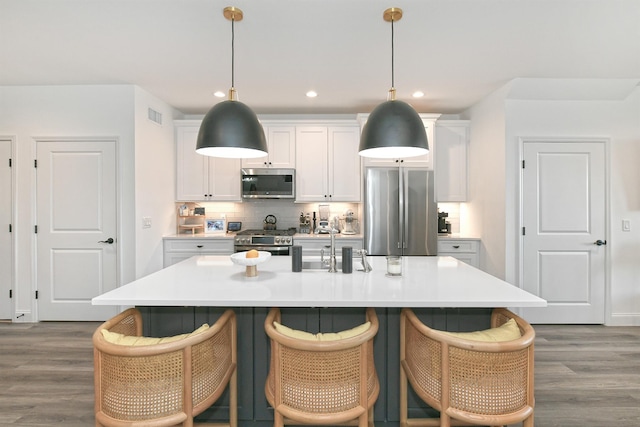 kitchen with a center island with sink, dark hardwood / wood-style flooring, white cabinetry, and appliances with stainless steel finishes