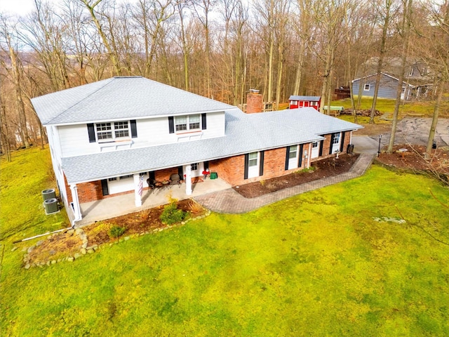 view of front of home with central air condition unit, a patio, and a front lawn