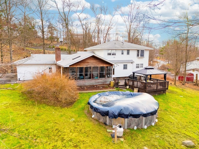 rear view of house featuring a gazebo, a sunroom, a swimming pool side deck, and a yard