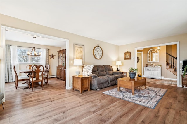 living room featuring baseboard heating, an inviting chandelier, and light wood-type flooring