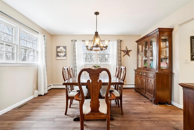 dining space featuring baseboard heating, a chandelier, and light wood-type flooring