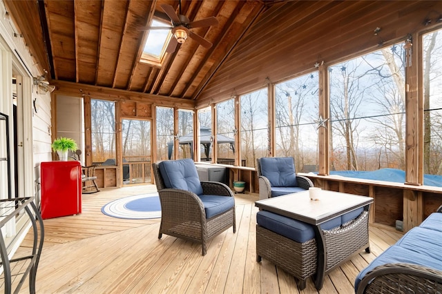 sunroom / solarium featuring ceiling fan, plenty of natural light, and vaulted ceiling with skylight