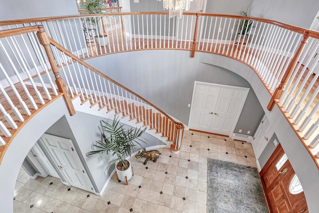 foyer with baseboard heating, a high ceiling, and a chandelier