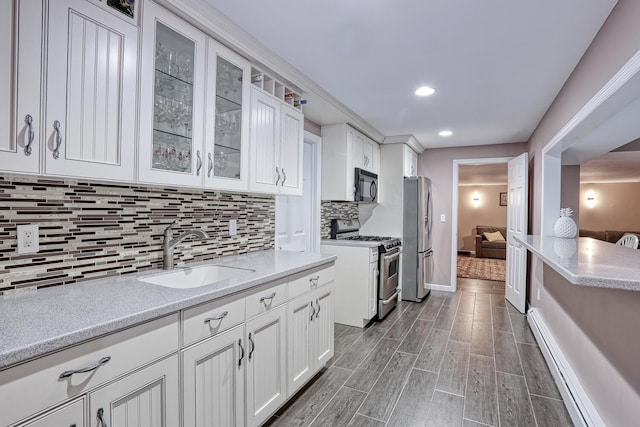 kitchen featuring white cabinetry, sink, stainless steel appliances, backsplash, and wood-type flooring