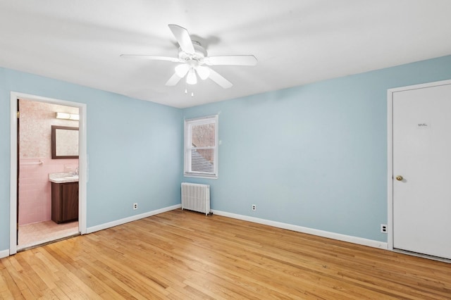 unfurnished bedroom featuring light hardwood / wood-style floors, ensuite bath, radiator, and ceiling fan