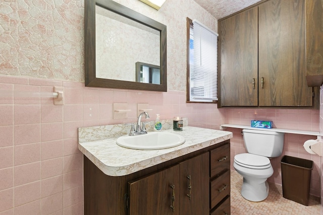 bathroom featuring vanity, toilet, and tile walls